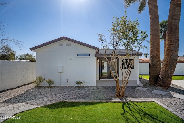 rear view of property featuring a lawn and fence