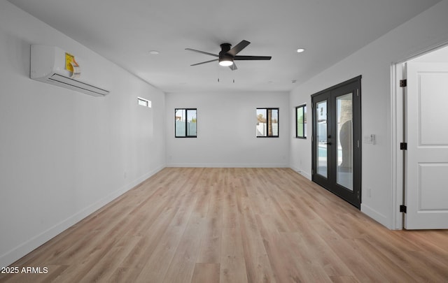 empty room with french doors, baseboards, light wood-style floors, and a wall mounted AC