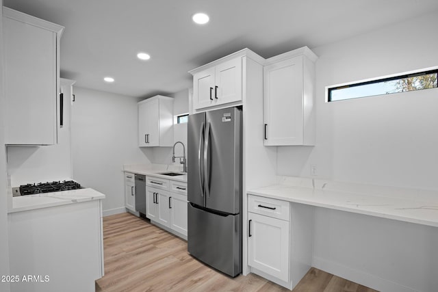 kitchen with light wood finished floors, recessed lighting, a sink, white cabinets, and appliances with stainless steel finishes