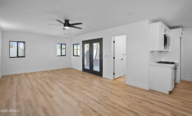 unfurnished living room featuring french doors, baseboards, light wood-style flooring, and a ceiling fan