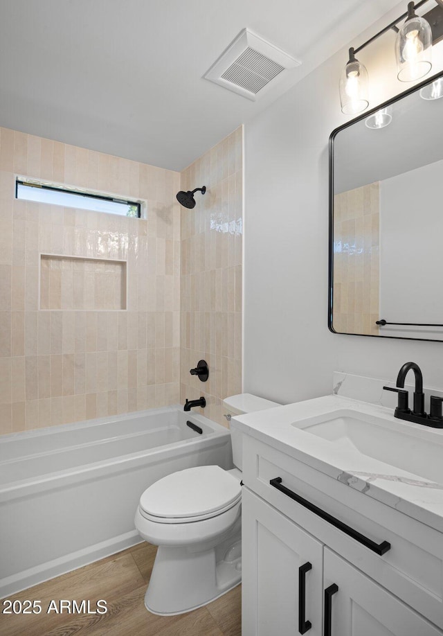 bathroom with visible vents, toilet, wood finished floors, shower / bath combination, and vanity