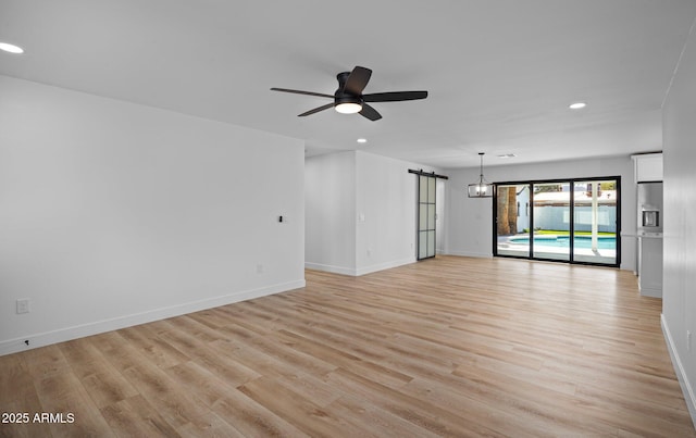 unfurnished room featuring light wood finished floors, baseboards, ceiling fan, a barn door, and recessed lighting