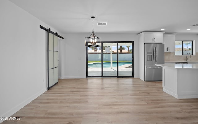 unfurnished dining area with a wealth of natural light, visible vents, a barn door, and a sink