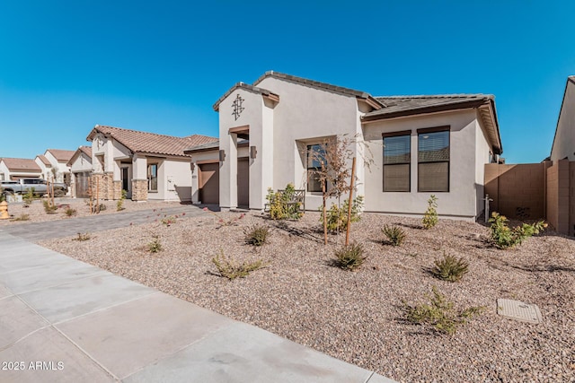 mediterranean / spanish home with driveway, a tile roof, fence, and stucco siding