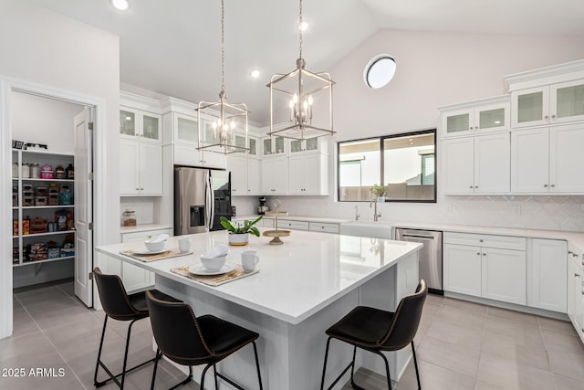 kitchen with appliances with stainless steel finishes, a kitchen island, and glass insert cabinets