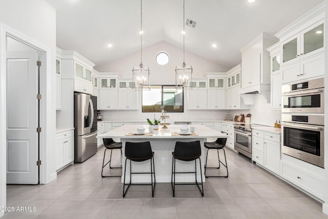 kitchen with light countertops, appliances with stainless steel finishes, a kitchen island, and glass insert cabinets