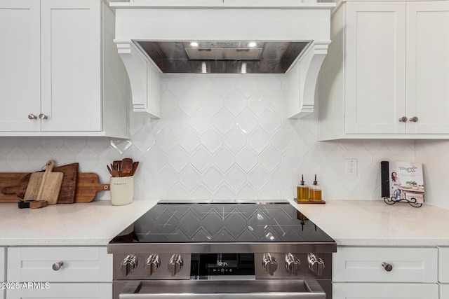 kitchen with stainless steel electric range oven, decorative backsplash, custom exhaust hood, and white cabinets