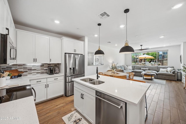 2628 S Voyager Dr Unit 104, Gilbert, AZ 85295 - kitchen featuring appliances with stainless steel finishes, a sink, tasteful backsplash, light wood-style flooring, and white cabinetry