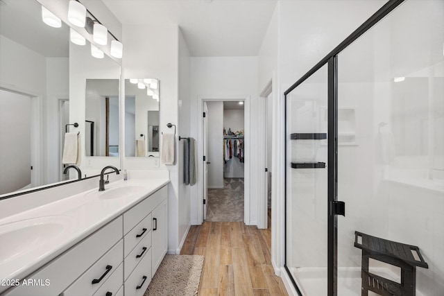 2628 S Voyager Dr Unit 104, Gilbert, AZ 85295 - bathroom with double vanity, a stall shower, a spacious closet, and wood finished floors