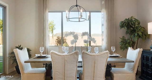 dining area with wood-type flooring, plenty of natural light, and an inviting chandelier