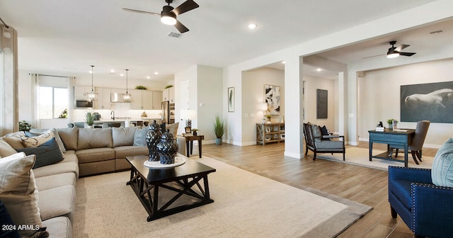 living room with sink, ceiling fan, and light hardwood / wood-style flooring