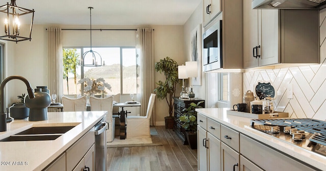 kitchen with tasteful backsplash, appliances with stainless steel finishes, hanging light fixtures, and hardwood / wood-style floors