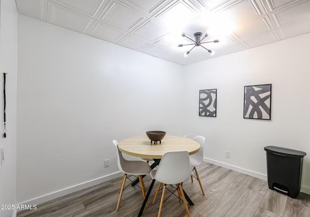 dining space with an ornate ceiling, baseboards, an inviting chandelier, and light wood-type flooring