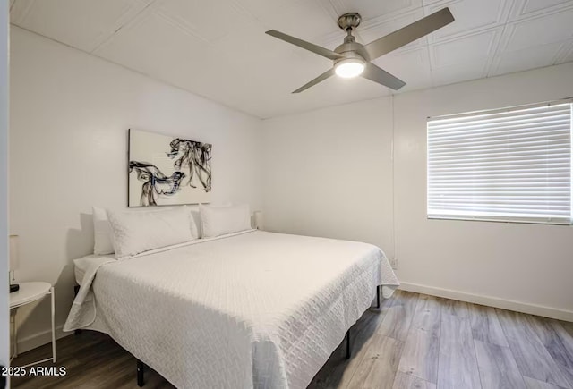 bedroom with baseboards, ceiling fan, and wood finished floors