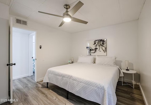 bedroom with visible vents, a ceiling fan, baseboards, and wood finished floors