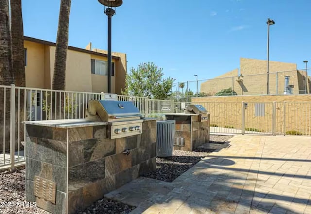 view of patio featuring a grill, fence, and an outdoor kitchen