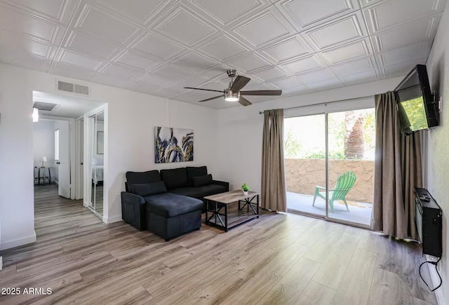living area featuring visible vents, light wood-style floors, ceiling fan, and an ornate ceiling