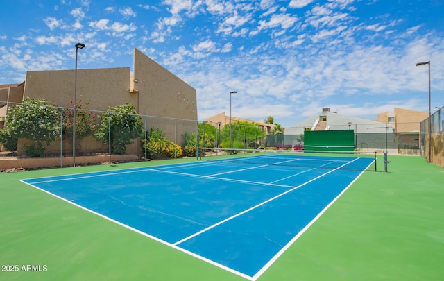 view of tennis court with community basketball court, fence, and a residential view