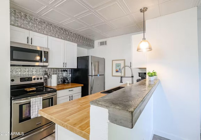 kitchen featuring a sink, wood counters, stainless steel appliances, a peninsula, and visible vents