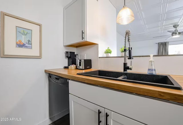 kitchen featuring a sink, dishwasher, wooden counters, white cabinetry, and pendant lighting