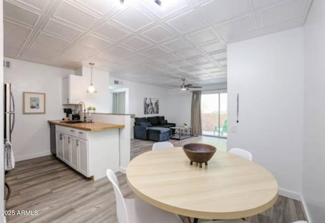 dining space with a ceiling fan, baseboards, and light wood-style floors