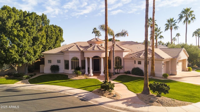 mediterranean / spanish home with a tiled roof, a front lawn, an attached garage, and stucco siding