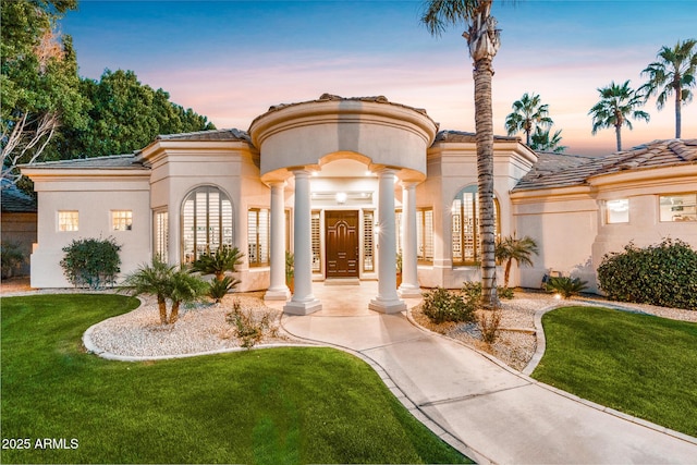 mediterranean / spanish house with a tiled roof, a front lawn, and stucco siding