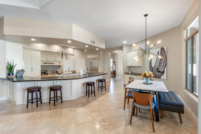 dining room with visible vents, arched walkways, baseboards, a notable chandelier, and recessed lighting