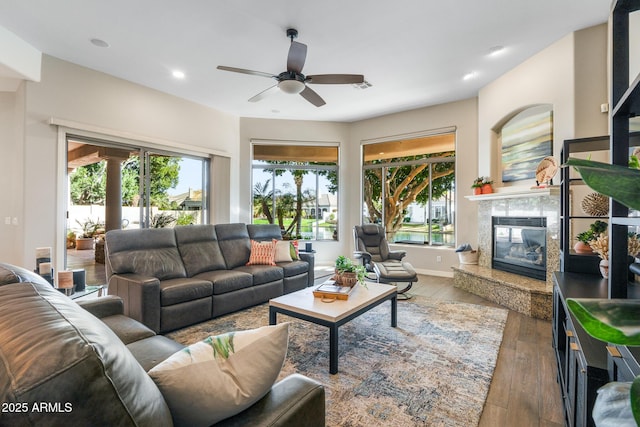 living room featuring dark wood-type flooring, plenty of natural light, a fireplace, and recessed lighting