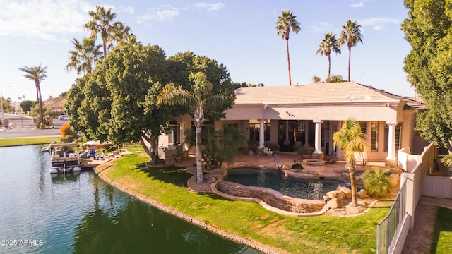 back of property featuring a patio area, a yard, a water view, and fence