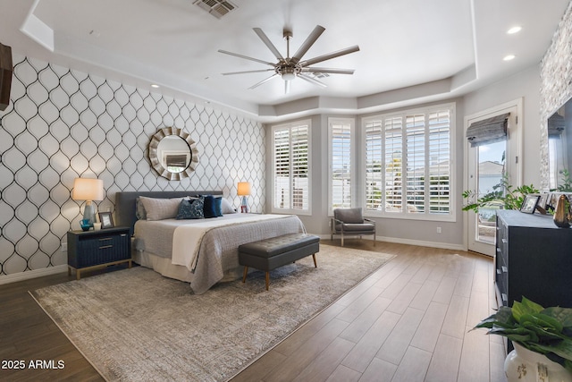 bedroom with access to exterior, a tray ceiling, visible vents, an accent wall, and wallpapered walls