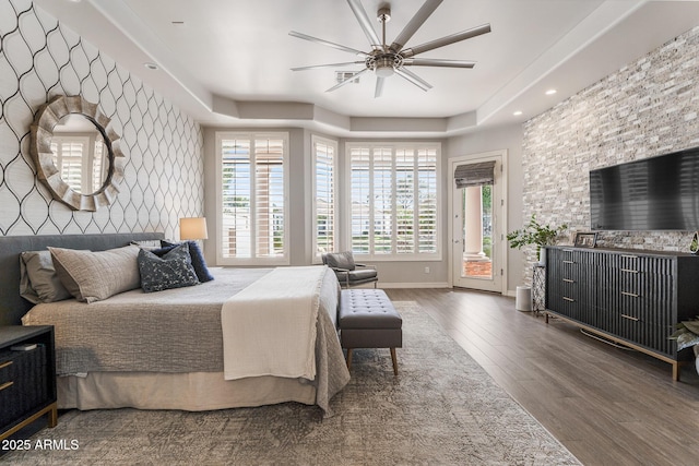 bedroom featuring baseboards, ceiling fan, dark wood-type flooring, access to exterior, and a tray ceiling