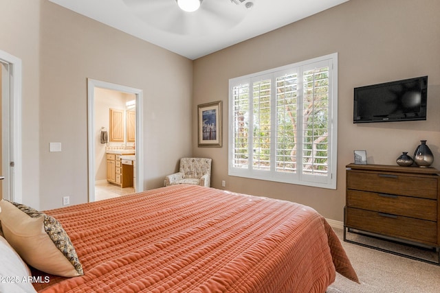 bedroom featuring light carpet, connected bathroom, a ceiling fan, and baseboards