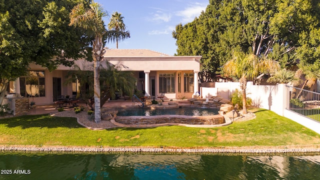 rear view of house featuring a water view, a patio area, a fenced backyard, and a yard