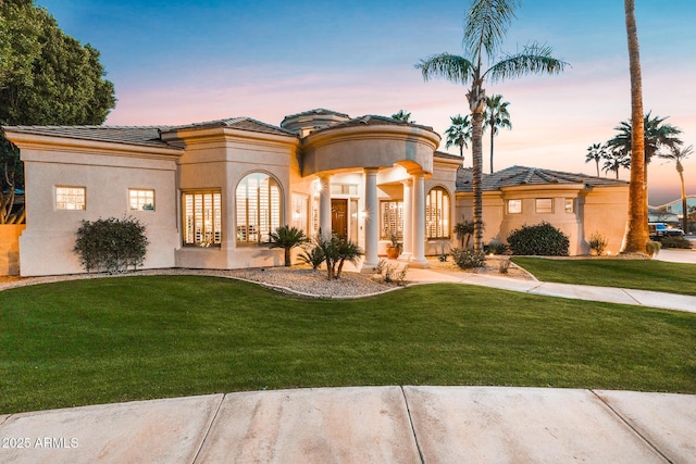 mediterranean / spanish home featuring a front lawn and stucco siding