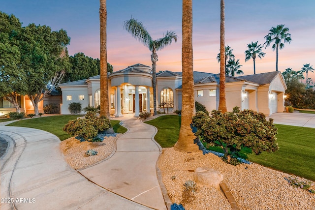 view of front of property featuring concrete driveway, a yard, an attached garage, and stucco siding