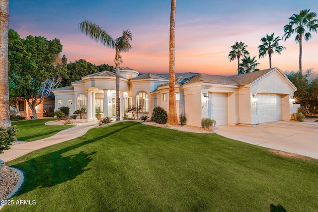 mediterranean / spanish-style home featuring concrete driveway, a lawn, an attached garage, and stucco siding