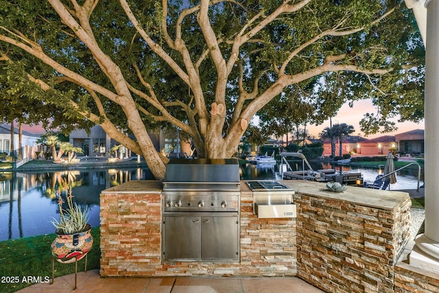 view of patio featuring exterior kitchen, a water view, and a bar