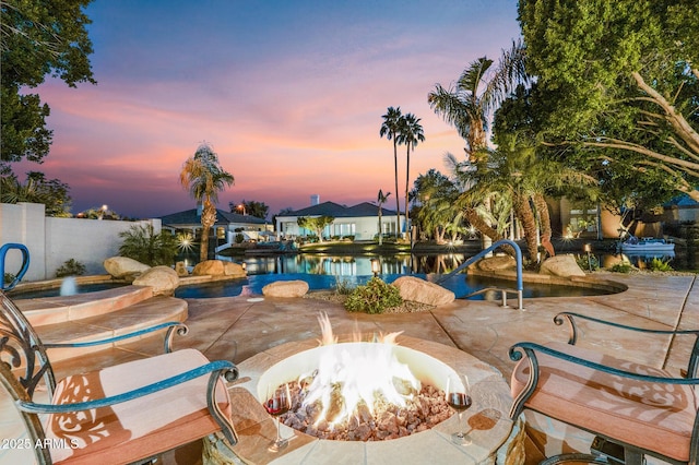 view of swimming pool featuring an outdoor fire pit, a patio area, a water view, and fence