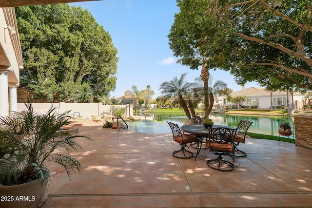 view of patio with a water view, fence, and outdoor dining area