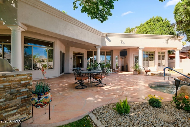 back of house with stucco siding, outdoor dining area, and a patio