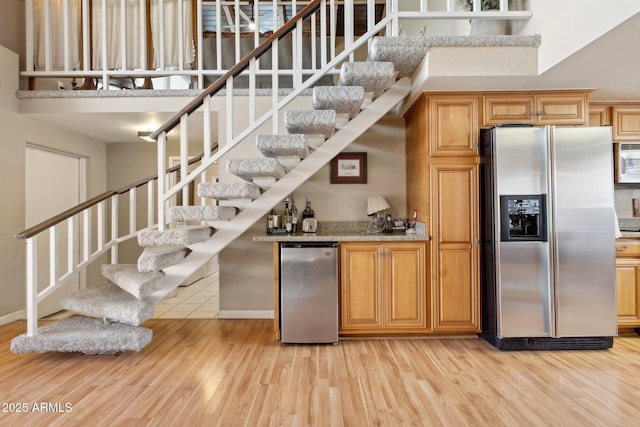 kitchen with light wood finished floors, white microwave, stainless steel refrigerator with ice dispenser, and refrigerator