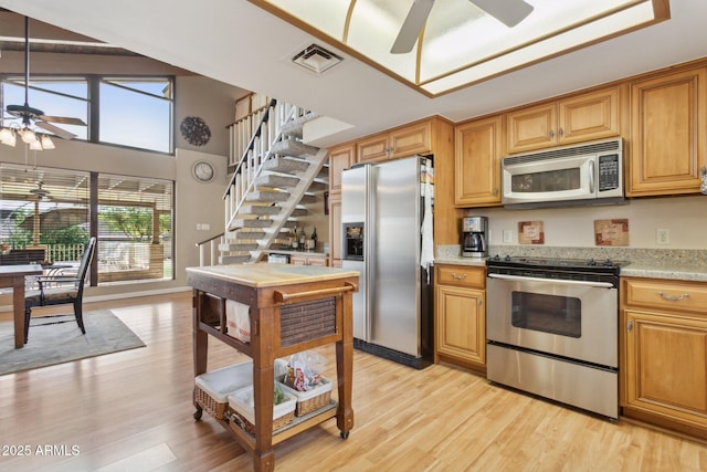 kitchen with stainless steel appliances, visible vents, light wood finished floors, and a ceiling fan