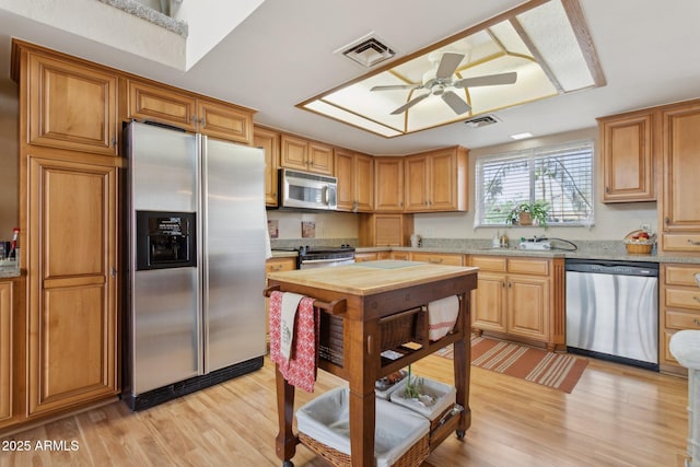 kitchen with appliances with stainless steel finishes, visible vents, light wood-style floors, and a sink