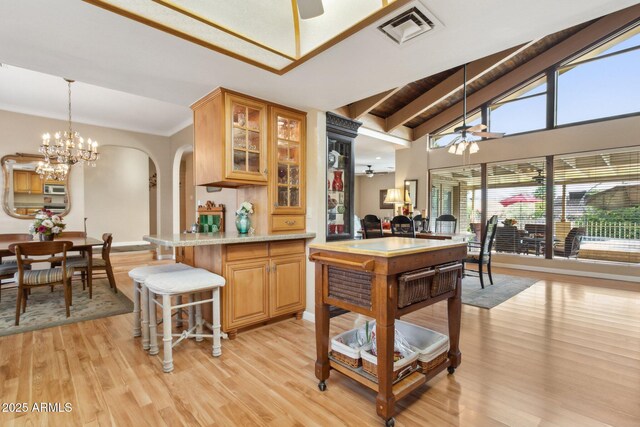 kitchen with glass insert cabinets, visible vents, stainless steel microwave, and ceiling fan with notable chandelier