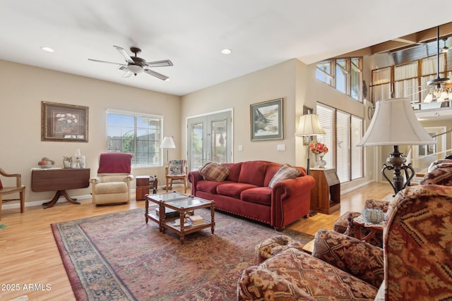 living area with a healthy amount of sunlight, ceiling fan, baseboards, and wood finished floors