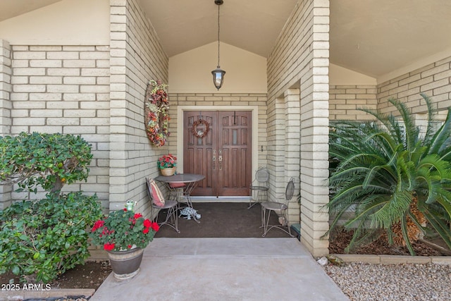 view of exterior entry featuring a porch and brick siding