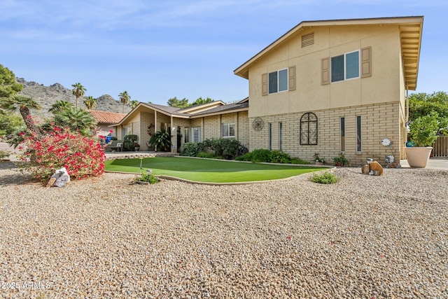 rear view of property featuring brick siding, a lawn, and stucco siding