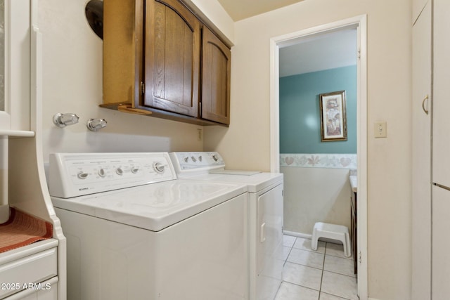 washroom featuring light tile patterned floors, washing machine and clothes dryer, and cabinet space