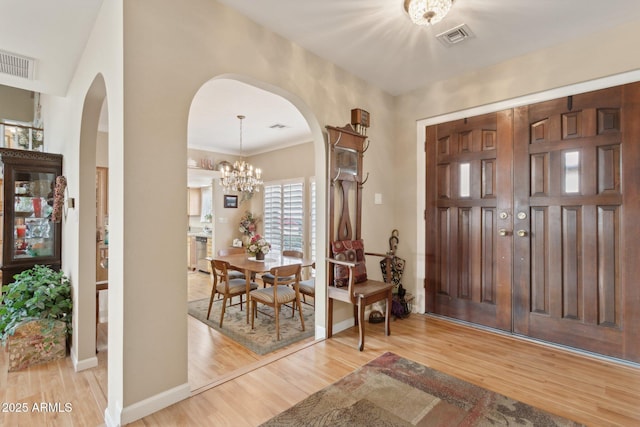 entrance foyer featuring a notable chandelier, baseboards, visible vents, and light wood-style floors